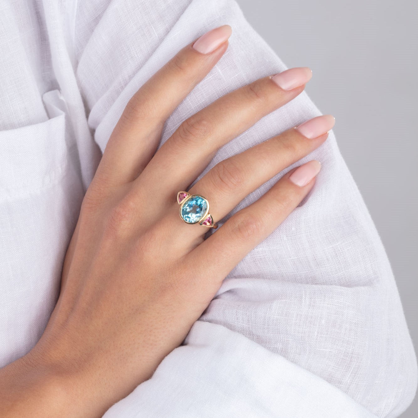 Blue topaz and pink tourmaline 18ct yellow gold ring pictured on model's hand