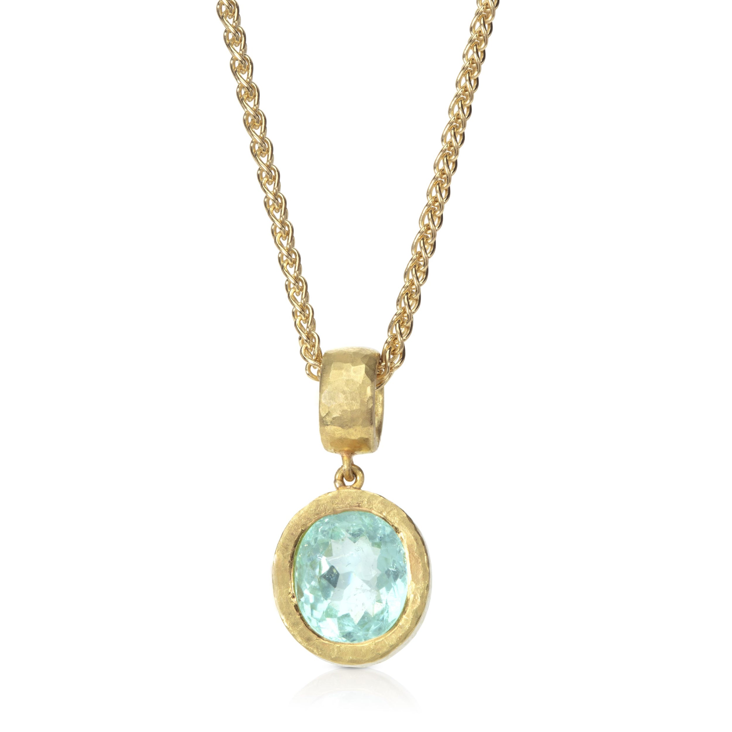 Paraiba tourmaline pendant in beaten gold setting on white background