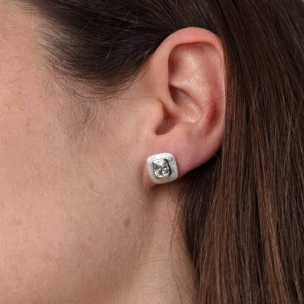 white sapphire and white gold stud earrings shown on a model