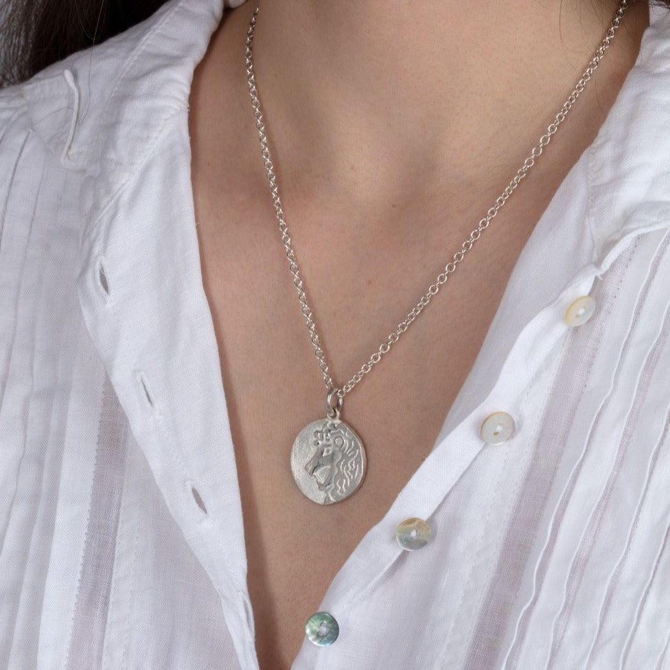 silver disk zodiac pendant necklace shown on a model