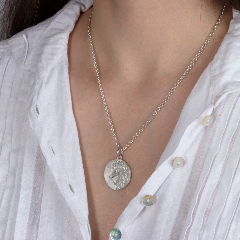 silver disk zodiac pendant necklace shown on a model