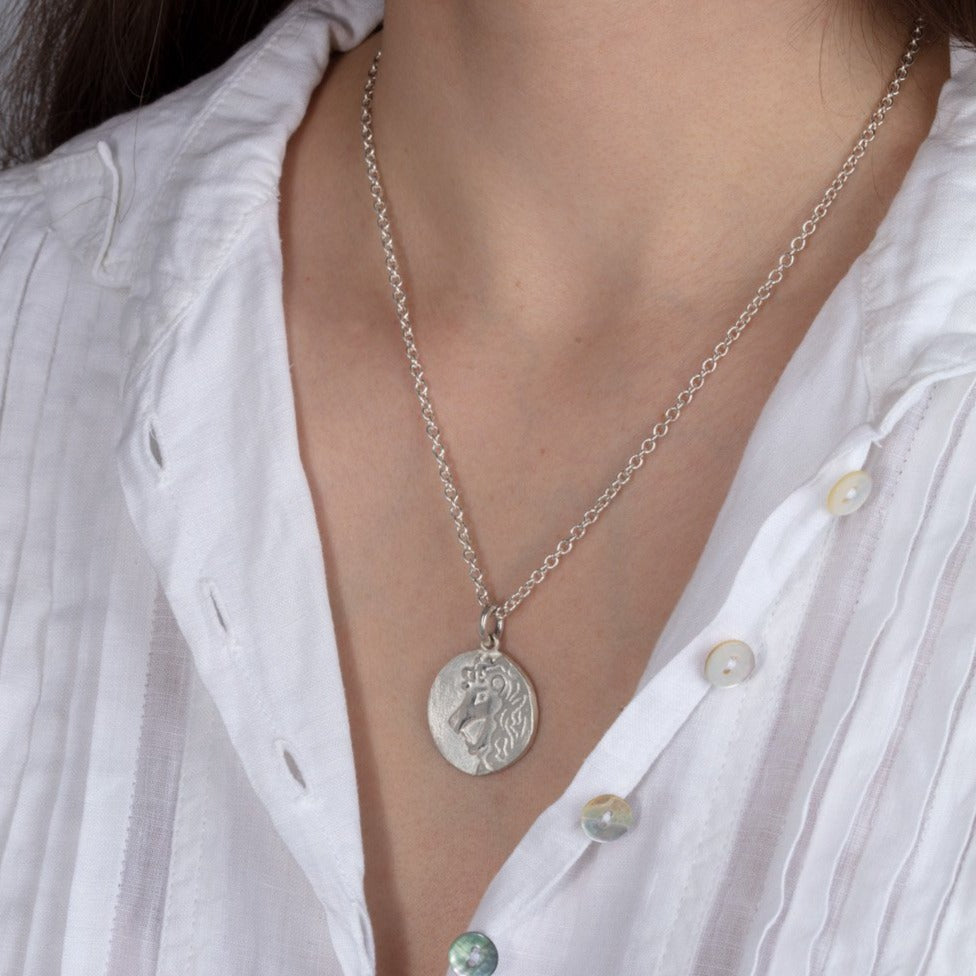 silver disk zodiac pendant necklace shown on a model