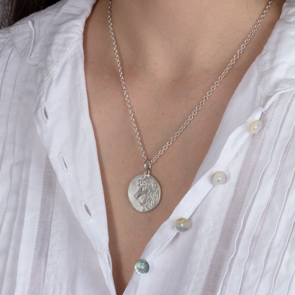 silver disk zodiac pendant necklace shown on a model
