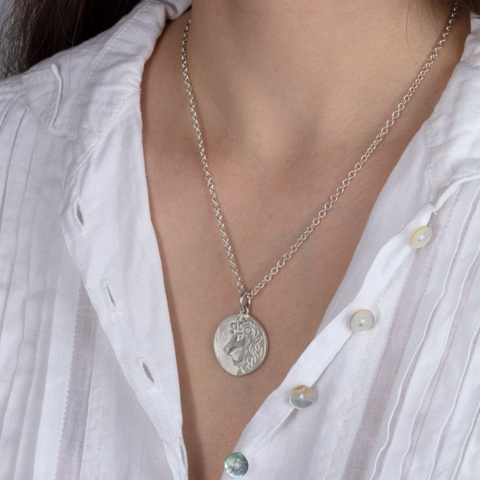 silver disk zodiac pendant necklace shown on a model