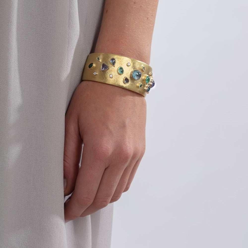 18ct yellow gold cuff bangle set with paraiba tourmalines and diamonds pictured on a model