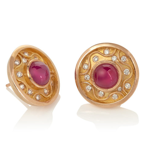 Round stud earrings with central ruby cabochon surrounded by raised zigzag pattern with diamonds