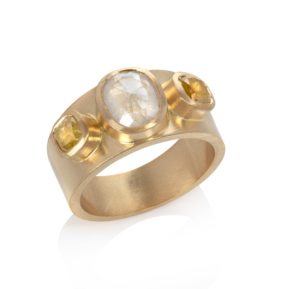 Wide yellow gold ring with three bezel set rose cut diamonds on white background