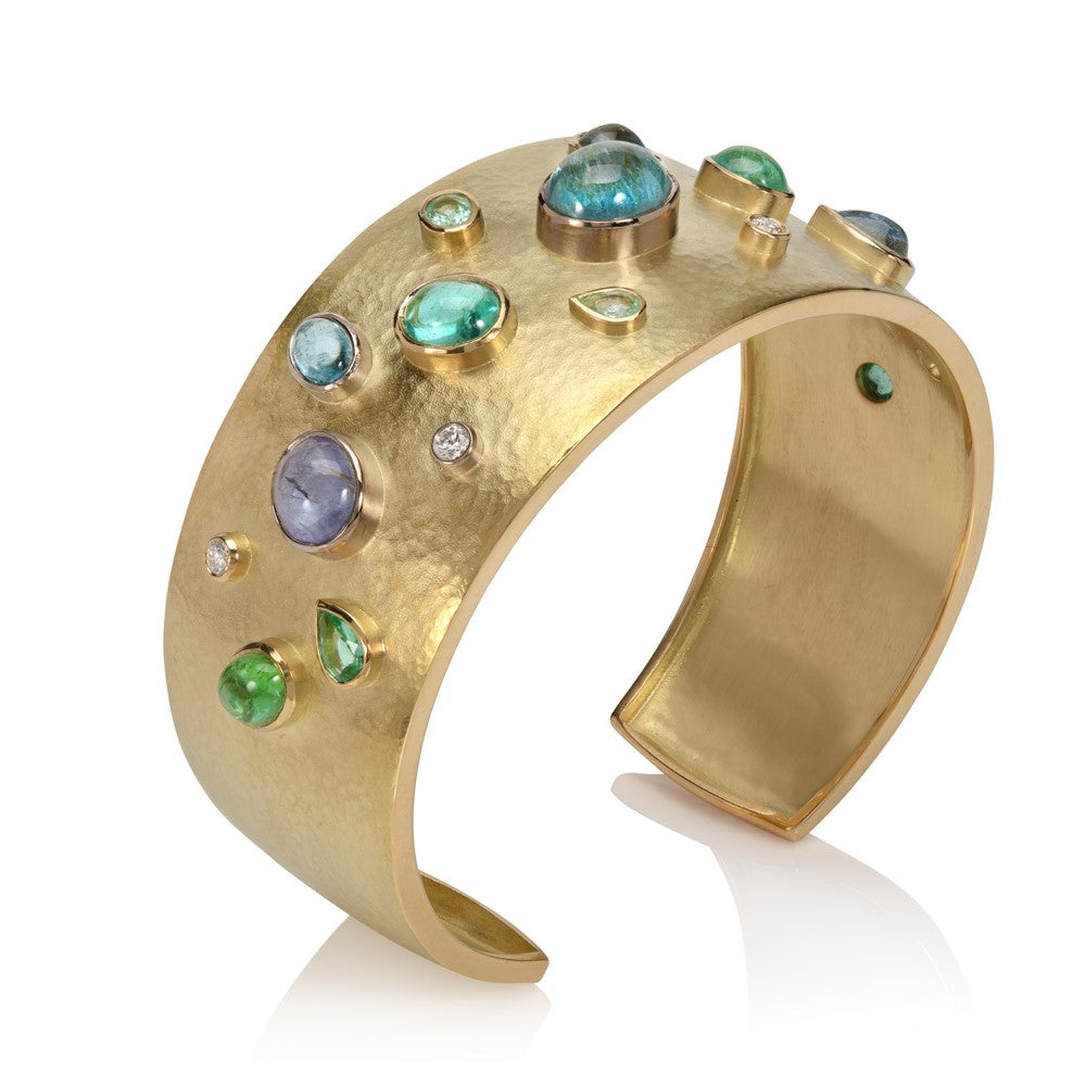 18ct yellow gold cuff bangle set with paraiba tourmalines and diamonds on a white background