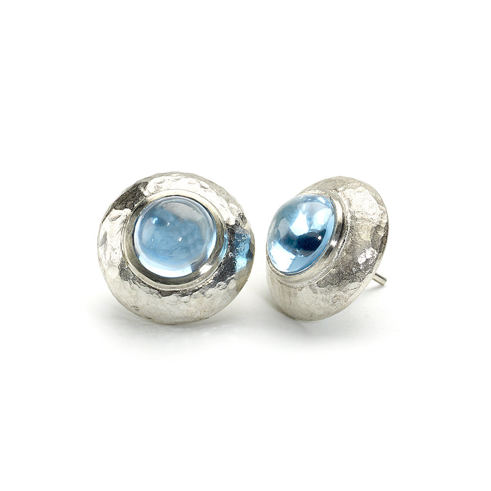 Stud earrings with round blue topaz cabochons set in hammered texture silver borders