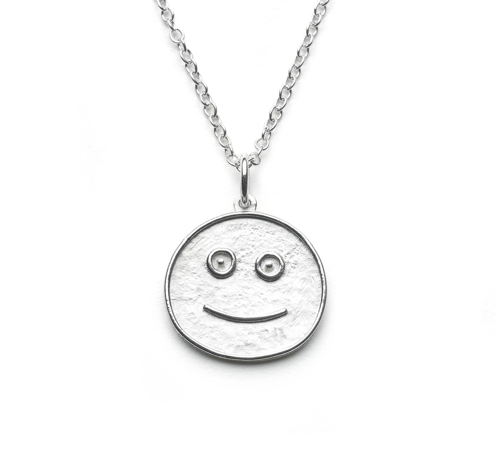 Silver pendant taking the form of a simplified smiley face hung on simple silver chain