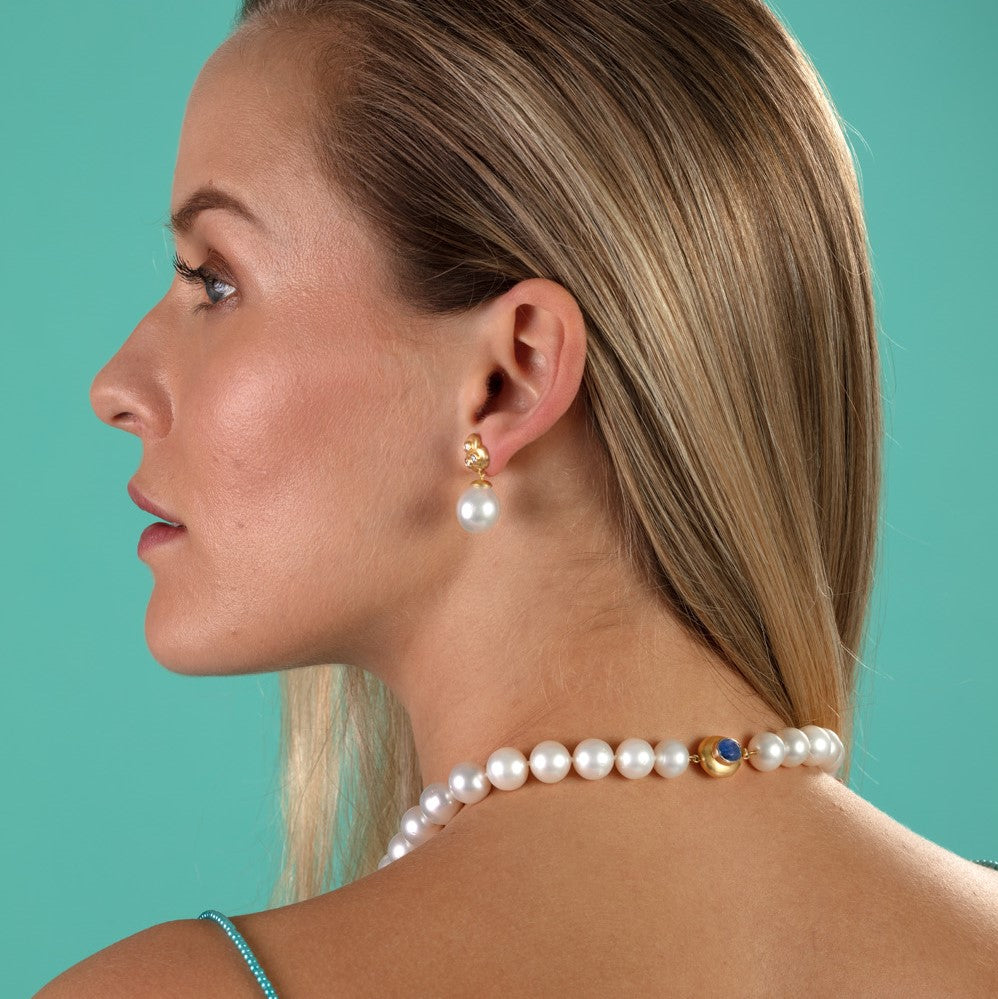 Model pictured wearing pearl earrings and pearl necklace