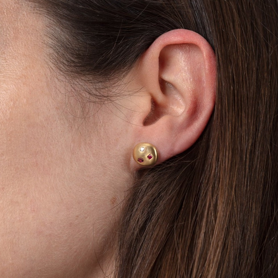 Gold, ruby and diamond stud earrings shown on a model