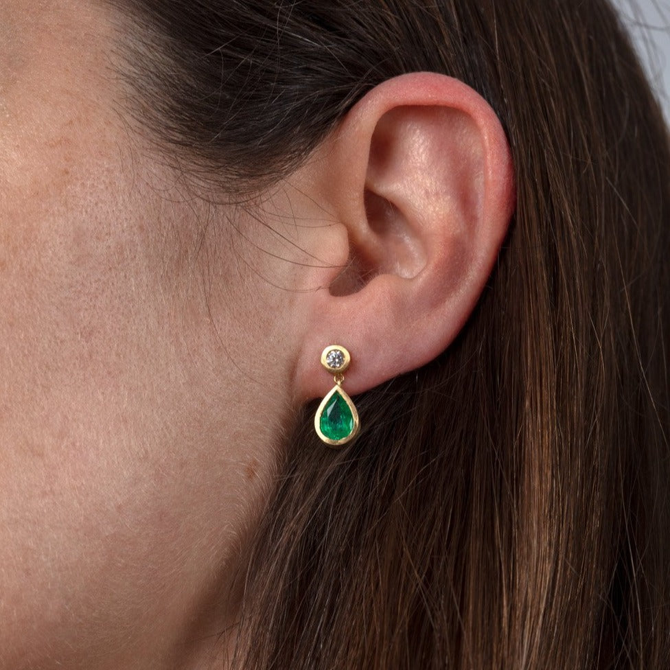 Diamond and emerald drop earrings shown on a model