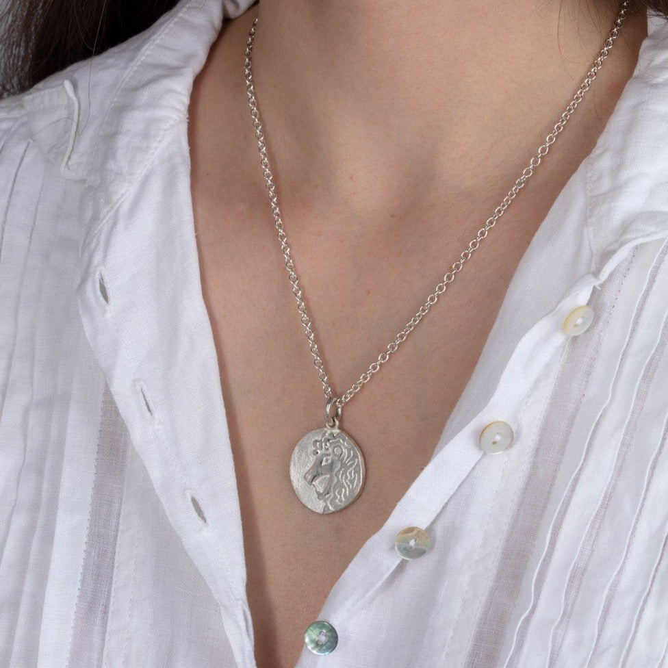 silver disk zodiac pendant necklace shown on a model