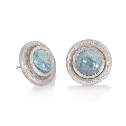 White gold stud earrings set with round aquamarine cabochon, finished with hammered texture