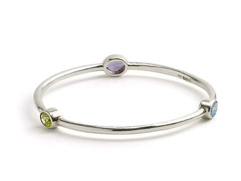 Silver bangle set with oval shaped blue topaz, amethyst and peridot