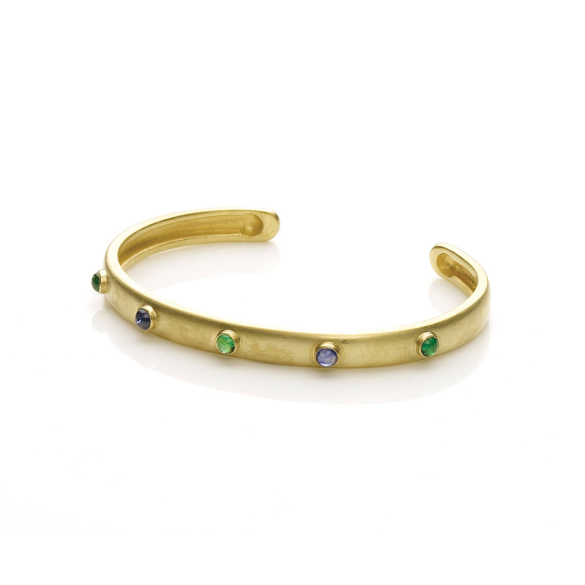 Oval yellow gold slip on bangle set with emeralds and sapphire cabochons on white background