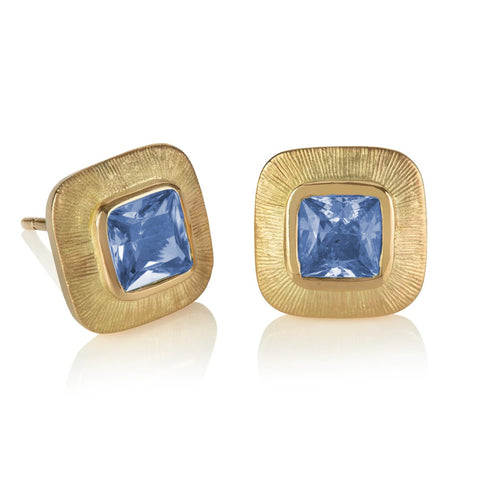 Cushion shaped blue sapphires set in wide engraved yellow gold borders