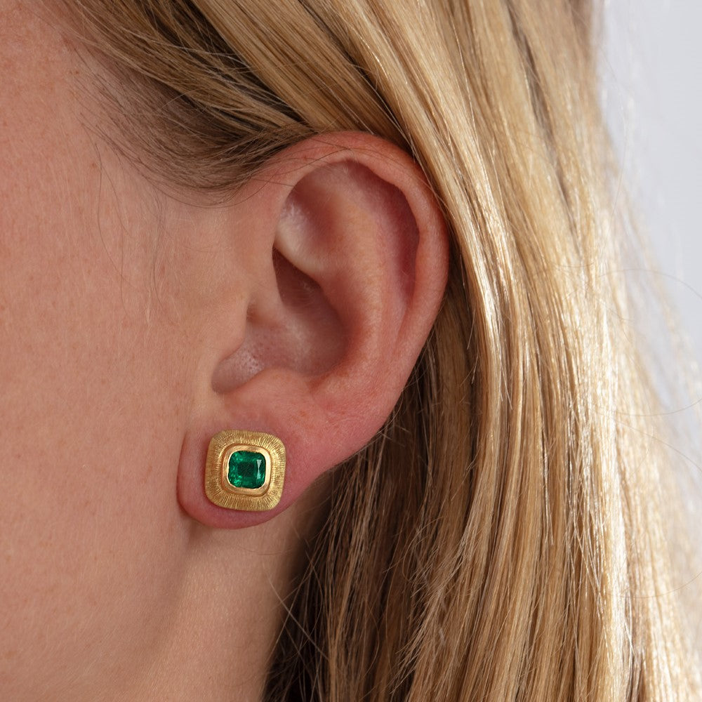 Emerald earrings with engraved borders pictured on model's ear
