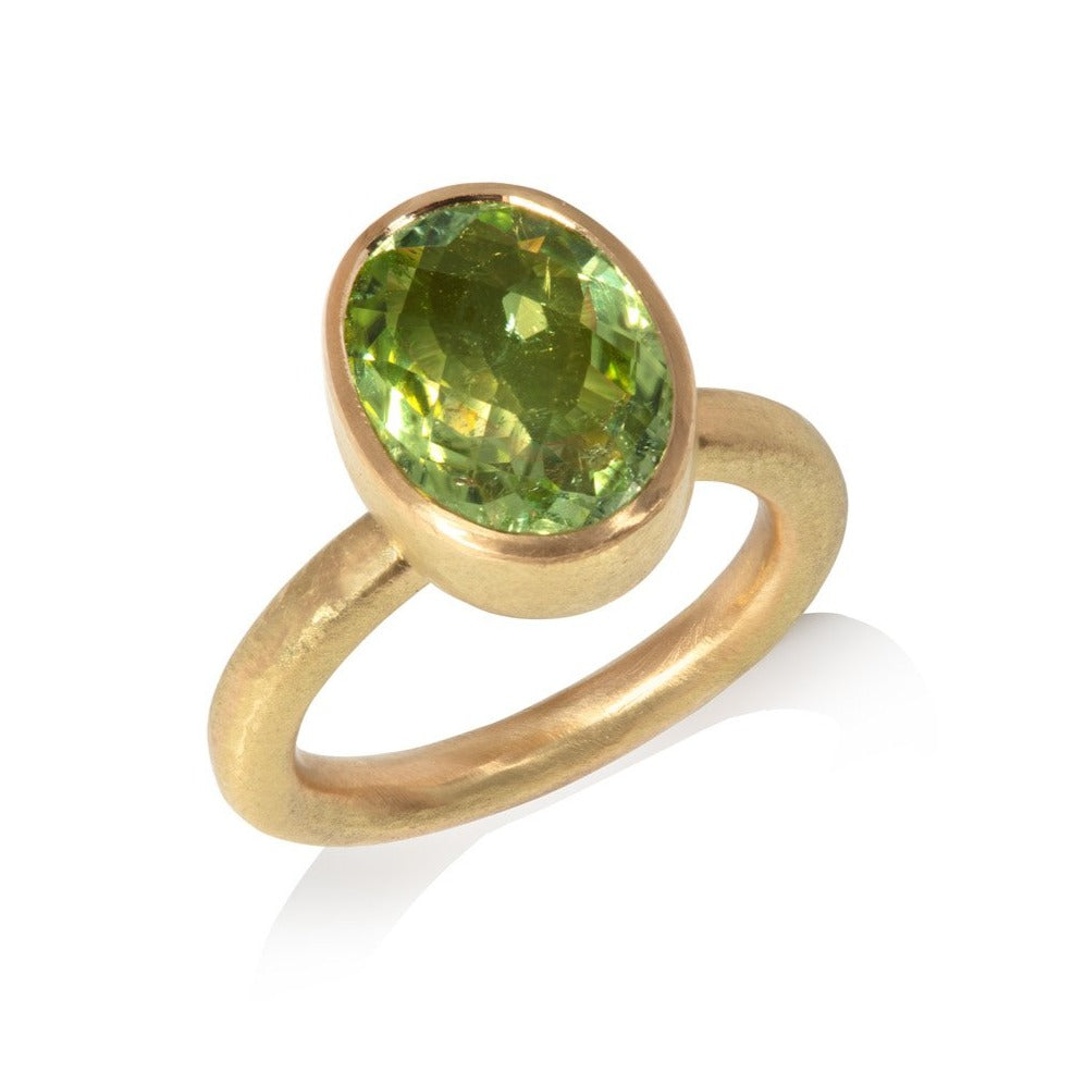 Green tourmaline and gold ring on white background