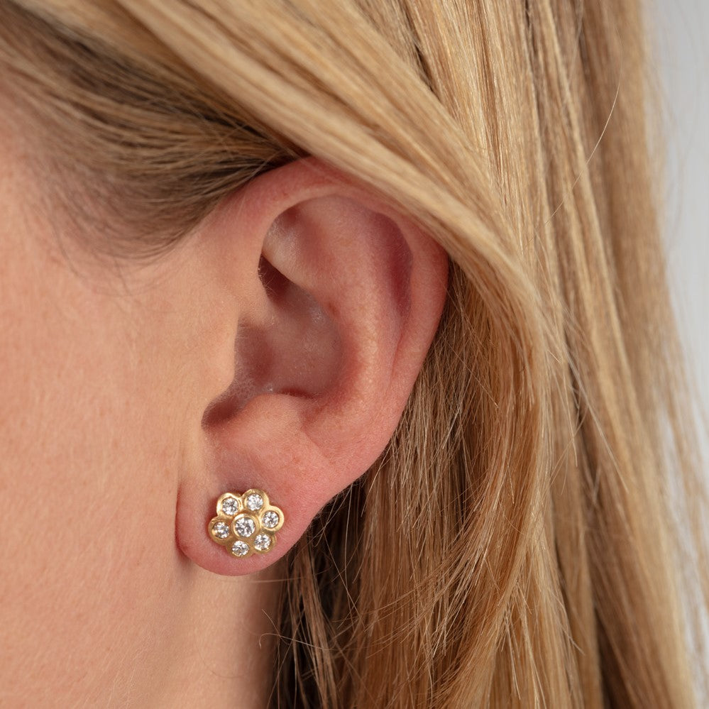 Diamond daisy stud earrings pictured on model's ear