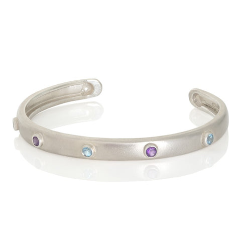 Silver bangle with blue topaz and amethyst on white background