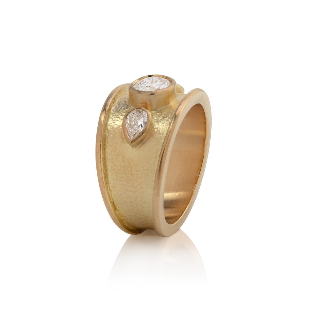 Wide yellow gold ring with thick border set with round cut diamond with two pear shaped diamonds, hammered texture finish, side view