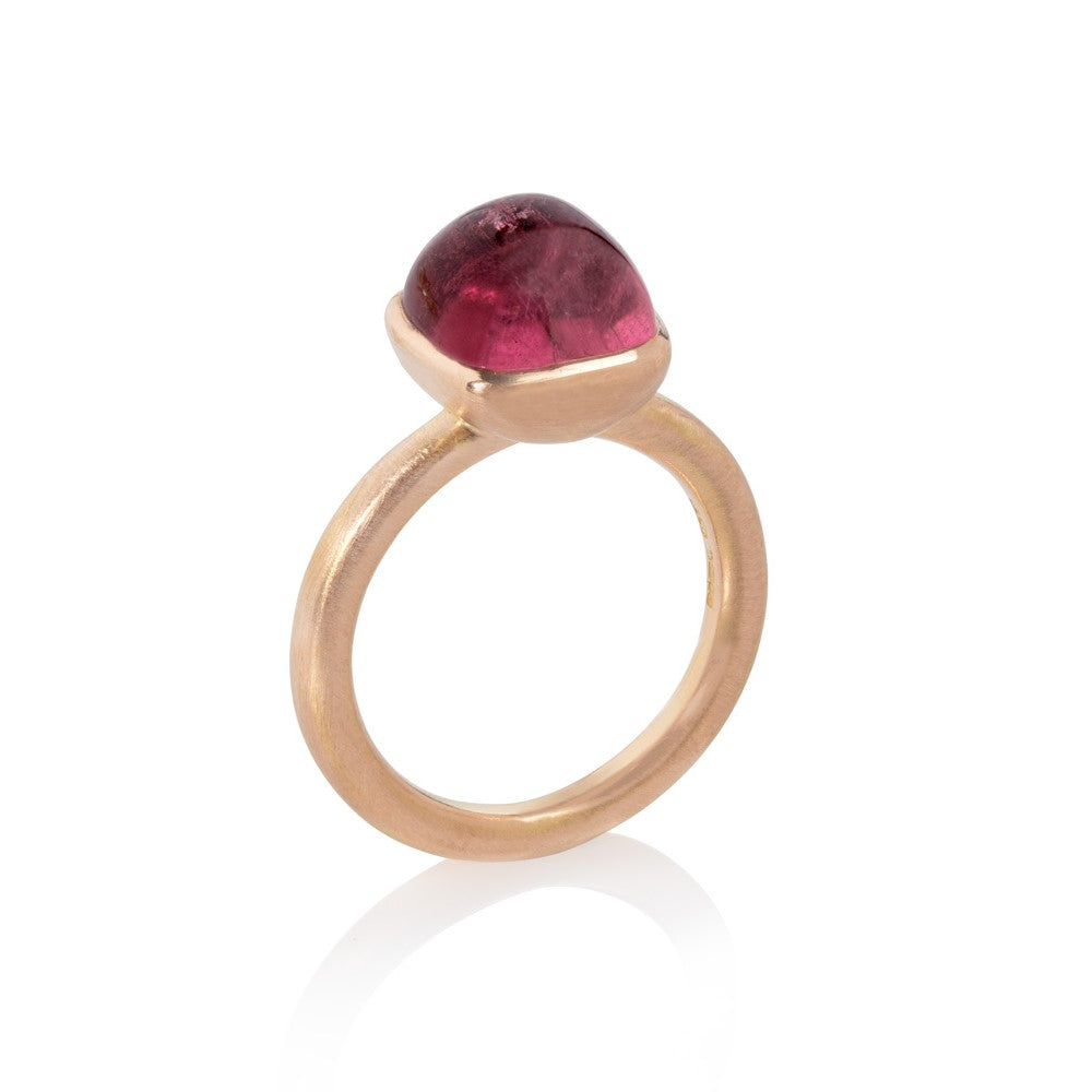Red gold ring set with large pink tourmaline cabochon on white background