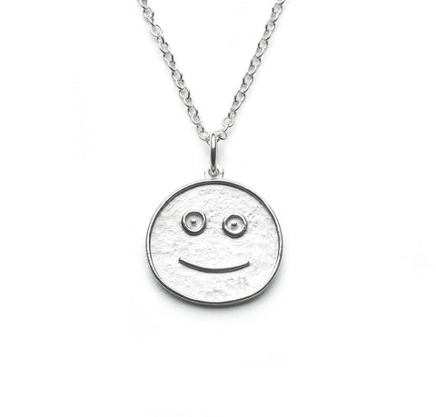 Silver pendant taking the form of a simplified smiley face hung on simple silver chain